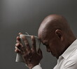 © herlanzer - man praying to god with hands together Caribbean man praying with black grey background with people stock image stock photo