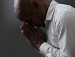 © herlanzer - man praying to god with hands together Caribbean man praying with black grey background with people stock image stock photo