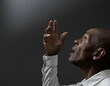 © herlanzer - man praying to god with hands together Caribbean man praying with black grey background with people stock image stock photo