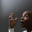 © herlanzer - man praying to god with hands together Caribbean man praying with black grey background with people stock image stock photo