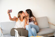 © ADDICTIVE STOCK - Lesbian couple kissing while taking a selfie at home