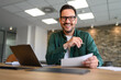 © Moon Safari - Portrait of handsome entrepreneur with laptop and documents smiling and working at desk in office