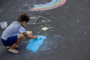 Wall Mural - the boy draws with chalk on the asphalt. Selective focus