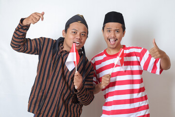 Portrait of two excited Asian man from Javanese and Madurese tribes celebrating independence day on 17 August while holding indonesian flag. Isolated image on white background