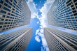 © samsusam - Modern skyscrapers in the city , low angle view, blue sky with clouds, symmetrical composition, geometric patterns on buildings