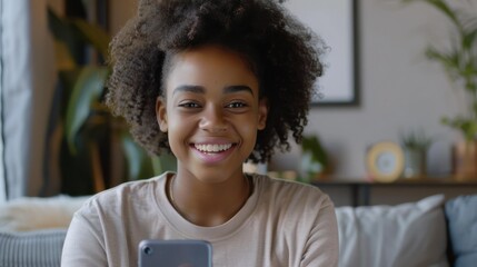 Wall Mural - Young happy African American teen girl holding phone looking at mobile vertical camera streaming vlog, taking selfie portrait, making call or recording video on cell at home. Cam view 