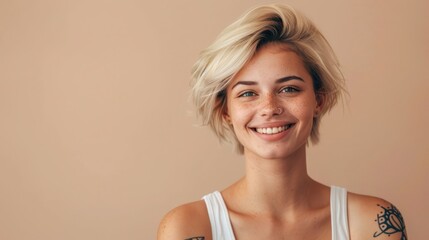 Wall Mural - Young happy blond pretty smiling girl beauty female gen z model with short blonde hair beautiful face healthy skin and tattoo looking at camera wearing white top isolated at beige background. 