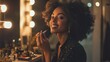 © Plaifah - A stylish image of a woman sitting at a vanity, applying lipstick with a confident smile, surrounded by an array of cosmetics and beauty tools in a well-lit setting.