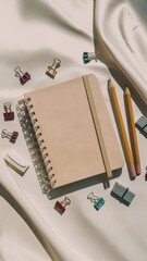 Sticker - A notebook, pencils and other office supplies on a white cloth, AI