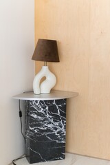 Aufkleber - A modern lamp with a unique design sits on a stylish marble side table, creating a contemporary and elegant atmosphere. The warm brown lampshade adds a cozy touch to the space.
