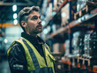 © Kowit - A man in a yellow vest stands in a warehouse looking at a shelf