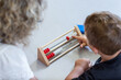 © wollertz - A teacher is helping a young boy with a wooden abacus. The boy is focused on the game, and the woman is patiently guiding him. Concept of learning and bonding between the two