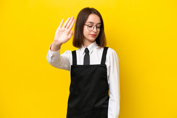 Young Ukrainian waitress woman isolated on yellow background making stop gesture and disappointed