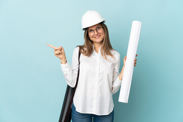 Slovak architect girl holding blueprints isolated on blue background pointing finger to the side