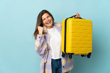 Young Slovak woman isolated on blue background in vacation with travel suitcase