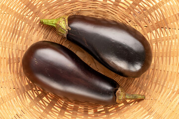 Two ripe eggplants in a straw dish, macro, top view.