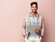 © Furqan - Happy young man poses with laptop against a pink background