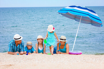 Wall Mural - A Happy family playing by the sea shore on the sand background