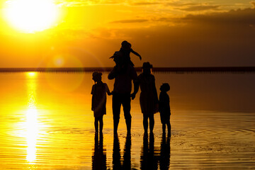 Wall Mural - A Happy family silhouette at sea with reflection in park in nature