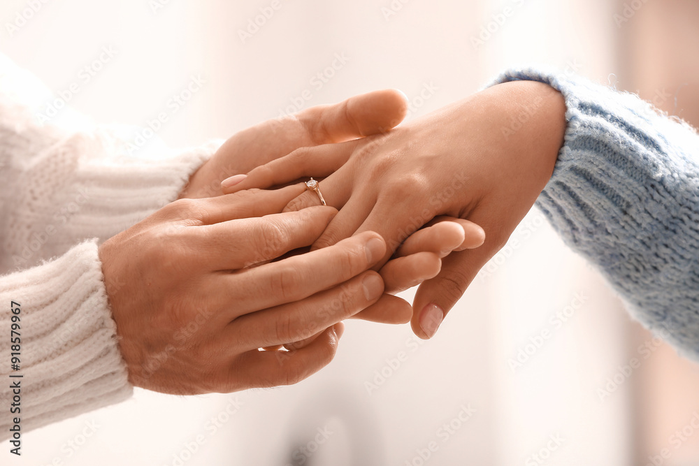 Man putting engagement ring on woman's finger, closeup