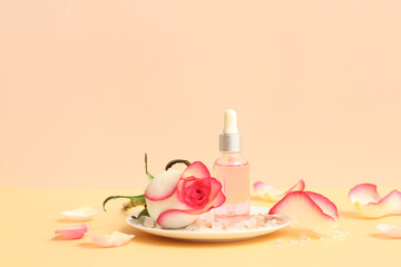 Wall Mural - Bottle of cosmetic oil with rose extract and flower on beige table