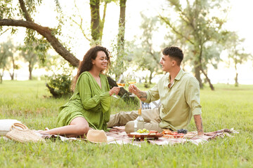 Wall Mural - Beautiful young happy couple with glasses of wine having romantic picnic in park