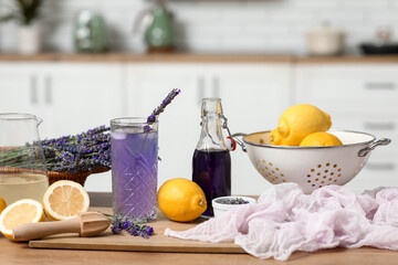 Wall Mural - Glass of fresh lavender lemonade with flowers and lemons on table in kitchen