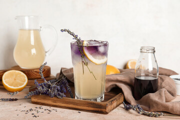 Wall Mural - Wooden board with glass of cold lavender lemonade, syrup and flowers on color table