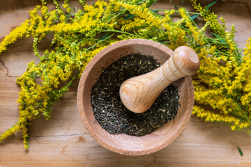 Flat lay composition with fresh yellow herbs and mortar on wooden table.