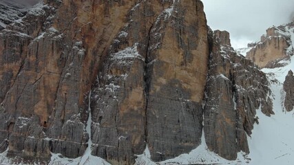 Wall Mural - Aerial around view of amazing rocky mountains in snow under moody gray clouds, Dolomites, Italy, 4k