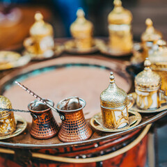 Traditional Turkish coffee set with ornate golden cups and copper pots