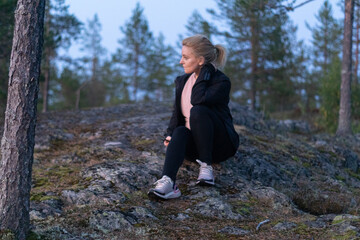 blonde woman hiking in the forest in Rovaniemi Finland Lapland, on a white night in summer with sunset