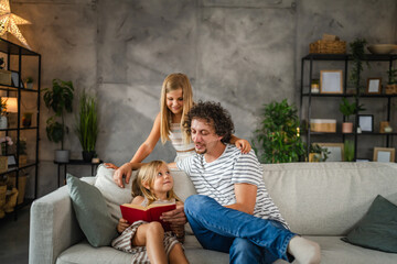 Young girl caucasian child read a book to her father and older sister