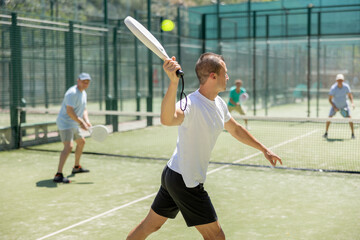 Wall Mural - Active man with enthusiasm playing padel on the tennis court