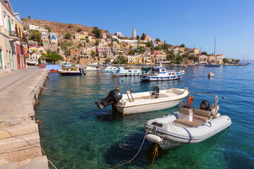 Wall Mural - Colourful house facades and fishing boats in the bay of Symi village at sunset.