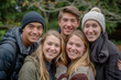 © Centric  - A group of five young adults smiling together outdoors, dressed warmly for a winter outing in a forest setting