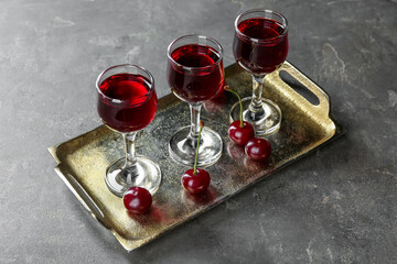 Canvas Print - Delicious cherry liqueur in glasses and fresh berries on grey table