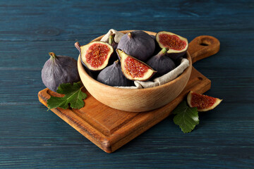 Wall Mural - Fresh ripe figs in a wooden bowl on a blue background