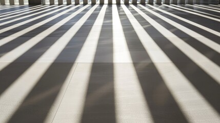 Poster - Shadows stretch across a modern floor, forming bold, alternating patterns as sunlight pours through vertical openings, offering a striking visual display