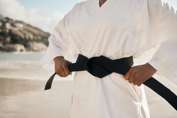 Canvas Print - Hands, beach and man with black belt, karate and fitness with pride for achievement, goal and nature. Fighter, workout and sensei with vacation, seaside and martial arts with training and practice