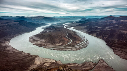 Wall Mural - Aerial view of a winding river carving through a majestic canyon, surrounded by rugged mountains and a vast desert landscape