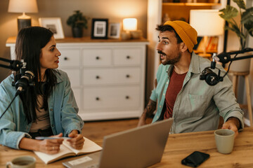 woman recording a radio podcast with male guest in studio