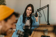 © La Famiglia - People in the podcast studio talking and recording, focus on a woman talking into a mic