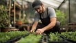 © Darunee - A farmer kneeling in a greenhouse, carefully tending to young plants