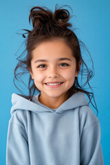 Canvas Print - A little girl in a blue hoodie smiles at the camera.