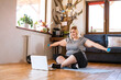 © Halfpoint - Online fitness training for overweight woman exercising at home with dumbbells, looking at laptop. Workout in living room.