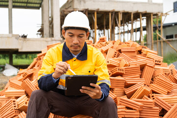 Wall Mural - A male architect in a hard hat and safety vest reviews construction documents He collaborates with the construction contractor, focusing on the house structure, iron framework, brickwork,roof design.