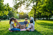 © Halfpoint - Children learning about renewable energy and solar panels during sustainable education class outdoors, using cardboard model of house wit solar panel on roof.