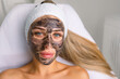© руслан малыш - cosmetologist applying black mask on pretty woman face wearing black gloves, gorgeous woman in spa having facial procedures