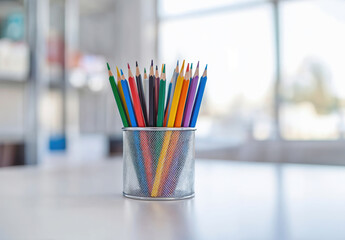 Wall Mural - Colorful pencils standing in a pencil holder on a white desk with blurred background